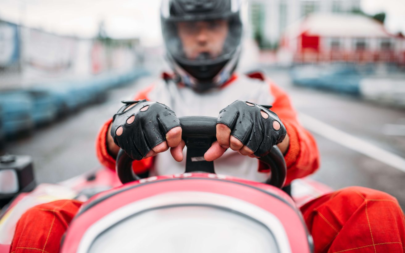 Karting race, go cart driver in helmet on carting speed track. Go-kart racer